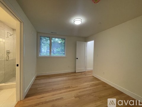A spacious room with wooden floors and a window.