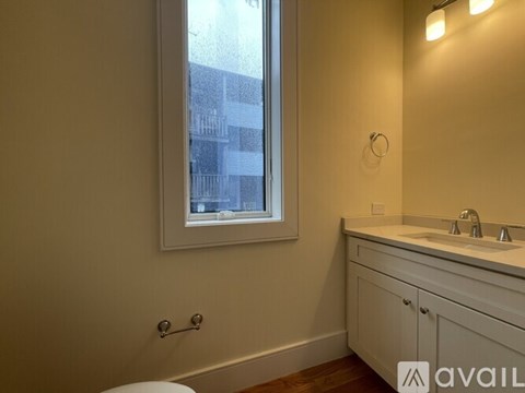 A bathroom with a toilet, sink, and a window.