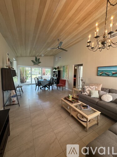 A living room with a wooden ceiling and a grey couch.