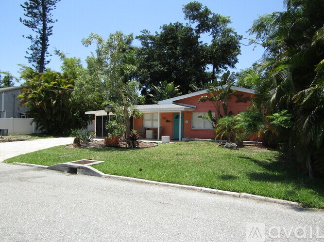 A house with a green door is surrounded by trees and bushes.