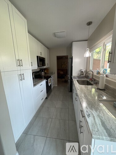 A kitchen with white cabinets and a marble countertop.