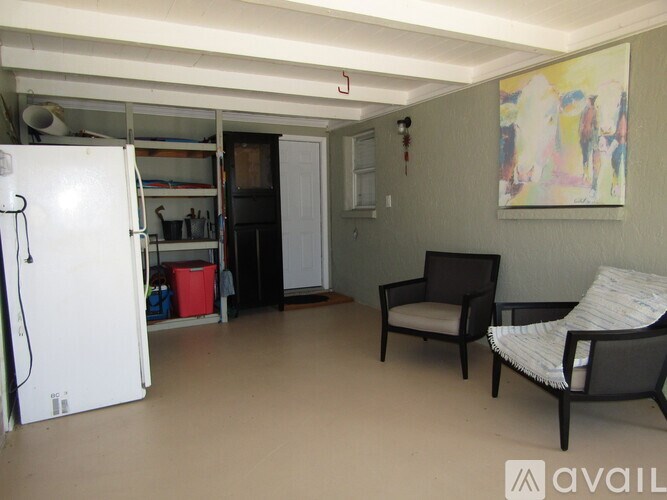 A kitchen area with a refrigerator, a chair, and a sofa.