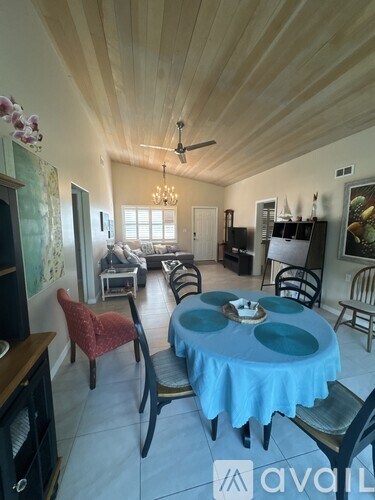 A dining room with a blue tablecloth and chairs.