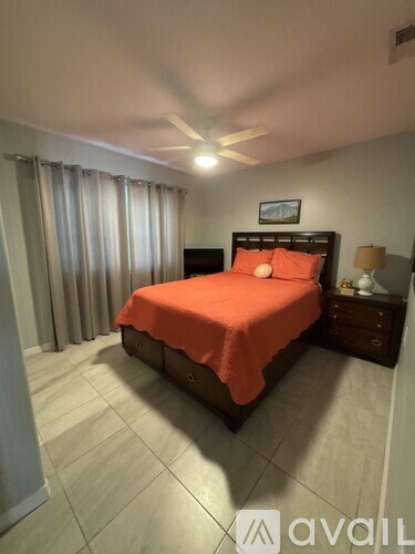 A bedroom with a bed covered in an orange bedspread.