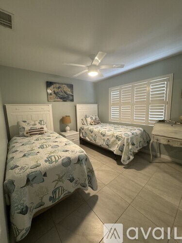 A bedroom with two beds and a ceiling fan.