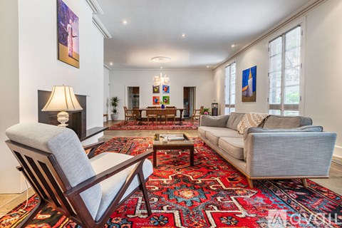 A living room with a rug and a chair.