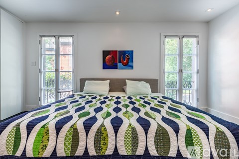 A bedroom with a large bed and a painting on the wall.