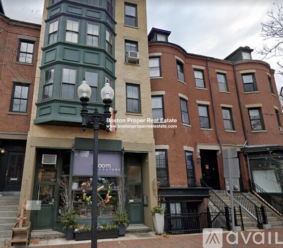A street view of a building with a sign for Boston Proper Real Estate.