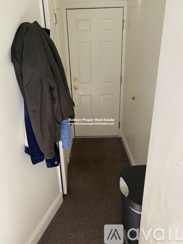 A hallway with a coat hanging on the wall and a door at the end.