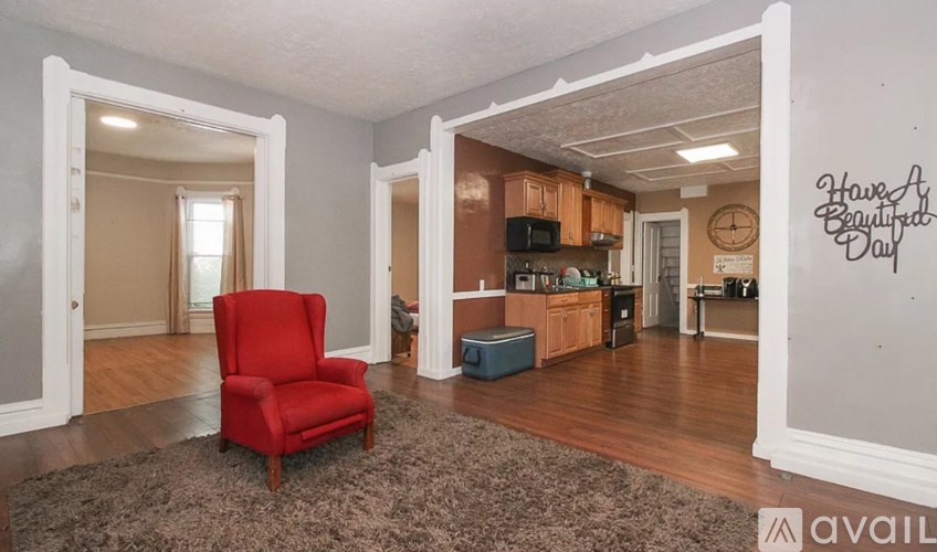 A red chair is in the middle of a room with a rug.