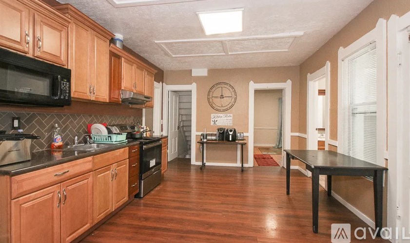 A kitchen with wooden cabinets and a black microwave.