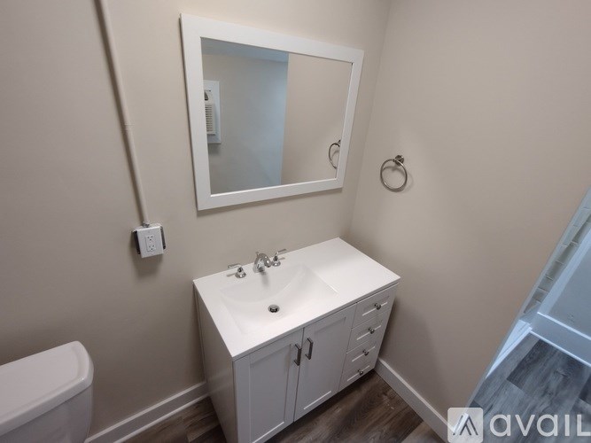 A white bathroom vanity with a mirror above it.