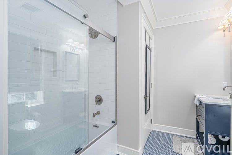 A bathroom with a glass shower door and a white wall.