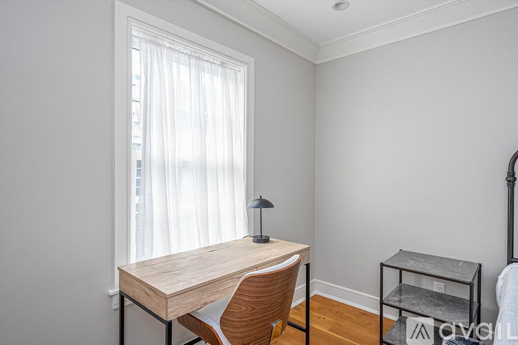 A room with a desk, chair, and lamp.