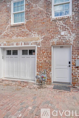 A white garage door is on the right side of a brick building.