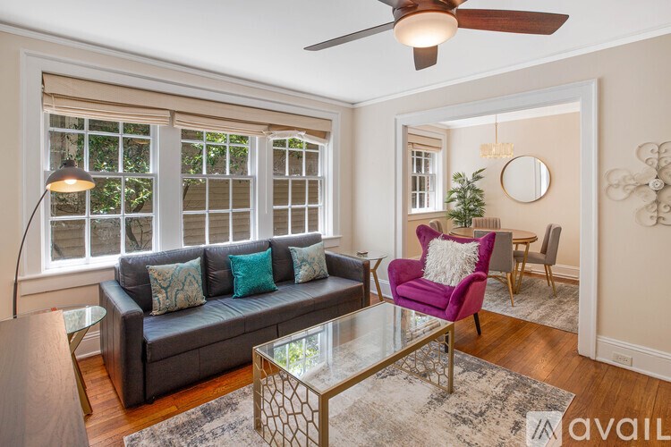 A living room with a couch, chair, and a fan.