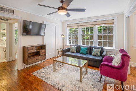 A living room with a purple chair and a black couch.