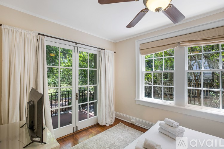 A room with a ceiling fan, sliding glass doors, and a flat screen TV.
