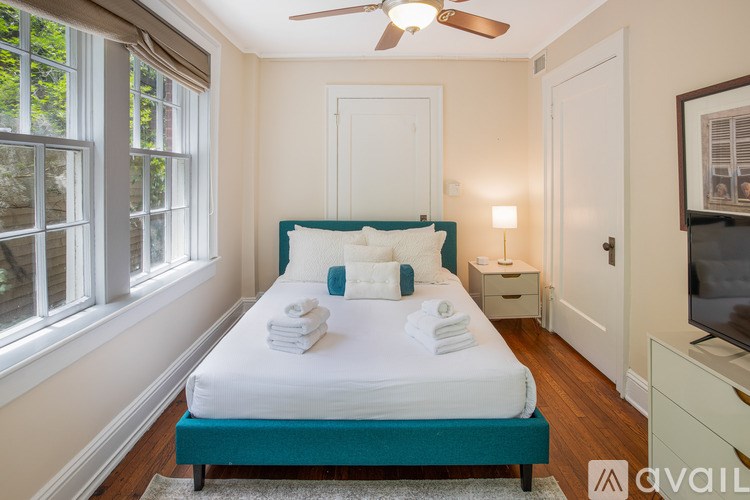 A bedroom with a bed, a window, a ceiling fan, and a dresser.