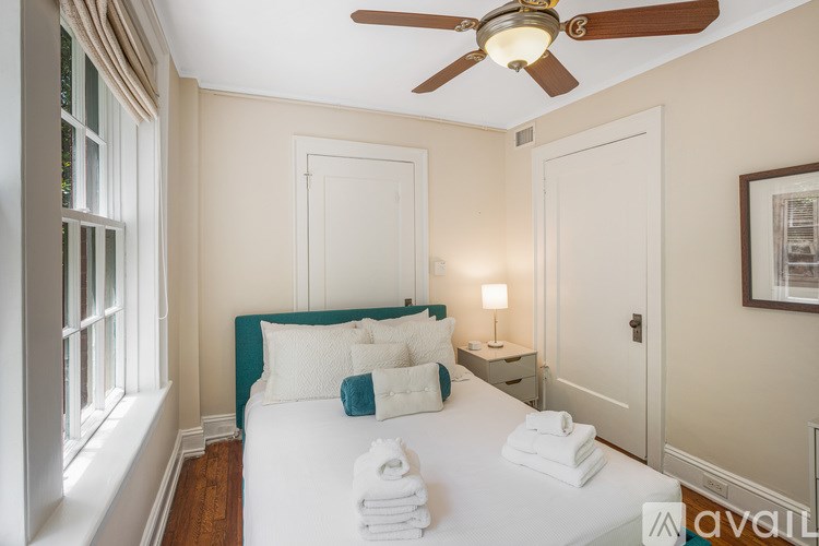 A bedroom with a bed, a ceiling fan, and a window.
