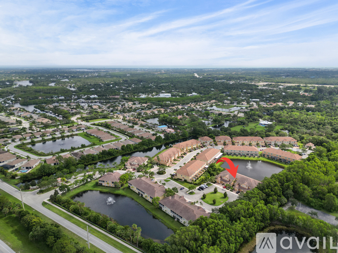 A bird's eye view of a residential area with a lake and a red arrow pointing to a specific house.