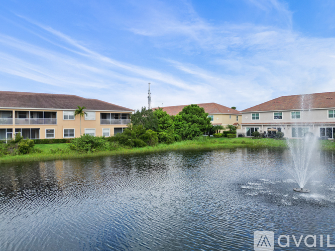 A fountain in the middle of a pond in front of a building.