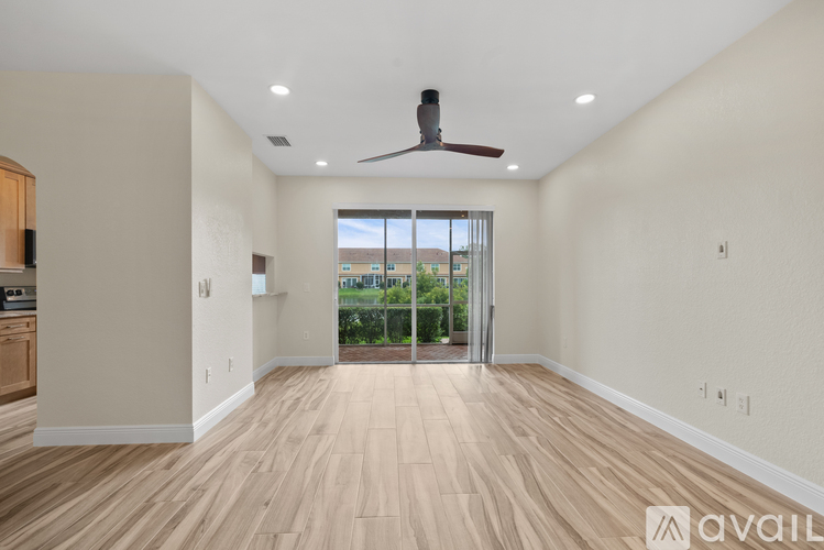 A spacious room with a ceiling fan and sliding glass doors leading to a balcony.
