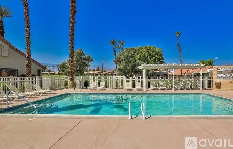 A pool surrounded by palm trees and deck chairs.