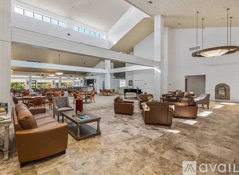 A spacious living room with brown leather furniture and a carpeted floor.