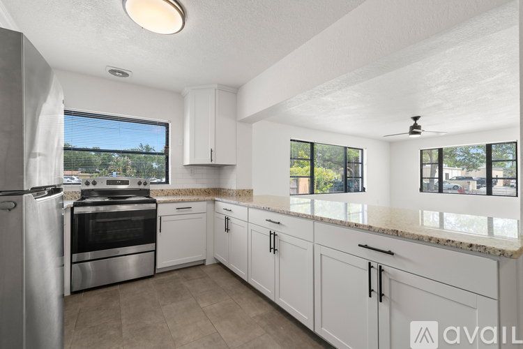 A kitchen with white cabinets and a stainless steel refrigerator.
