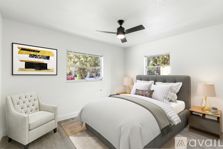 A bedroom with a large bed, a chair, and a painting on the wall.