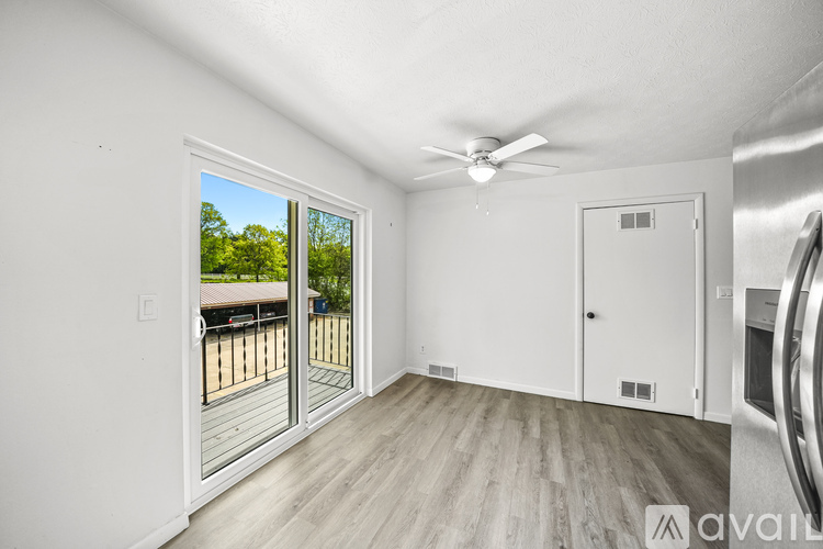 A room with a ceiling fan and a sliding glass door leading to a deck.