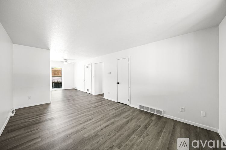 A spacious room with wooden flooring and white walls.