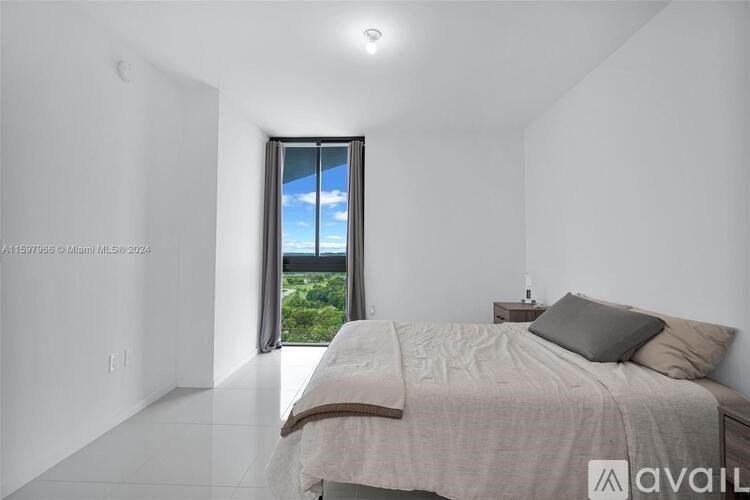 A bedroom with a large bed and a view of the sky through a window.