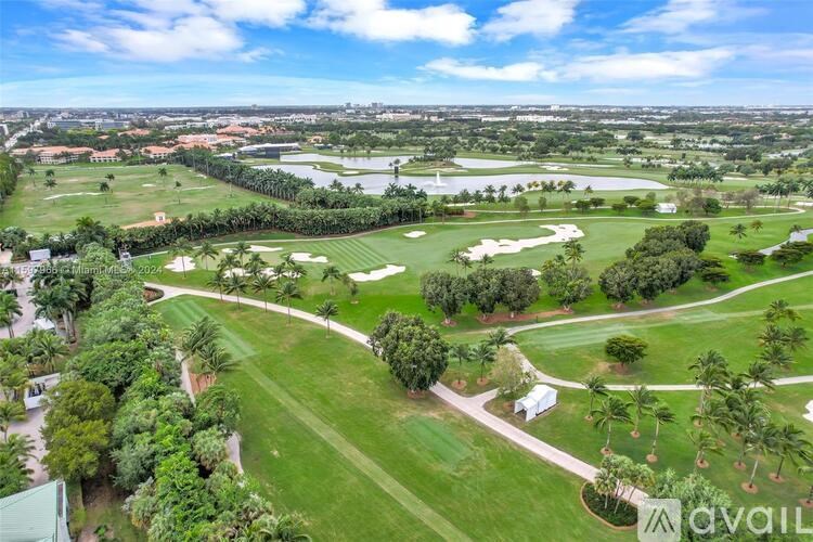 A golf course with a clear blue sky and a few clouds.