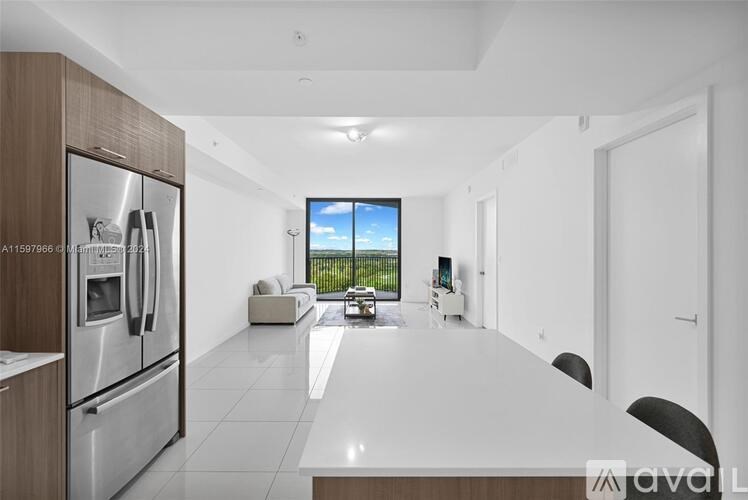 A modern kitchen with a refrigerator, a dining table, and a view of the backyard.