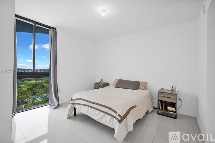 A bedroom with a large bed and a view of the trees outside the window.