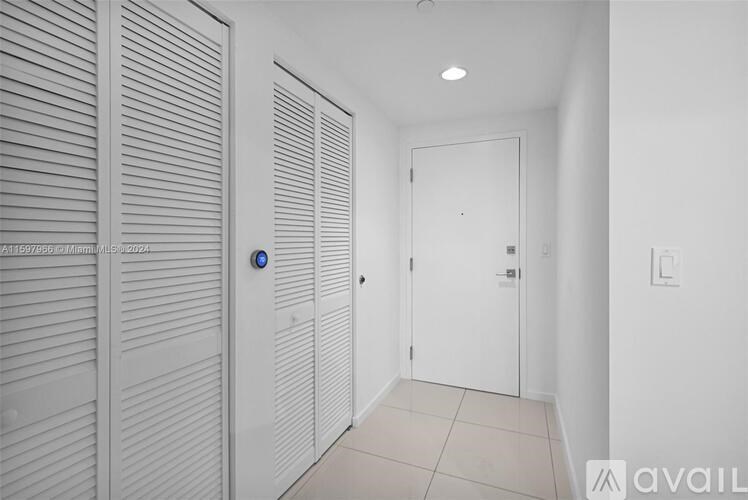 A hallway with a blue light switch and white walls.