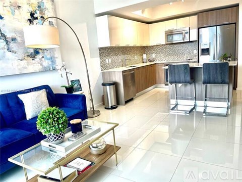 A blue sofa sits in a living room with a glass coffee table in front of it.