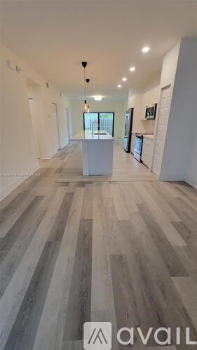 A spacious room with wooden flooring and white walls.