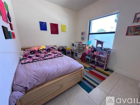 A bedroom with a bed, a window, and a shelf with various items.