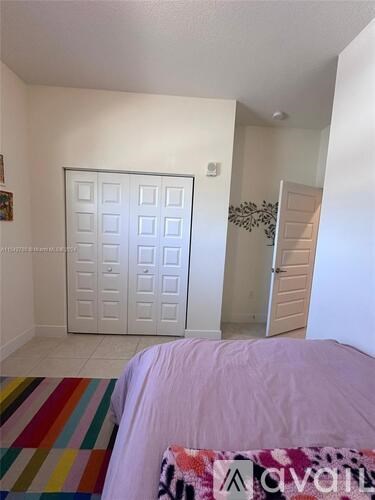A bedroom with a white door and a bed with a pink blanket.