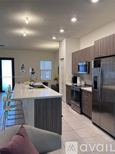 A modern kitchen with stainless steel appliances and a dining area.