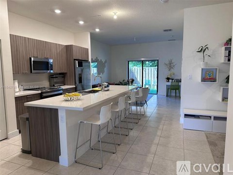 A kitchen with a white island and bar stools.