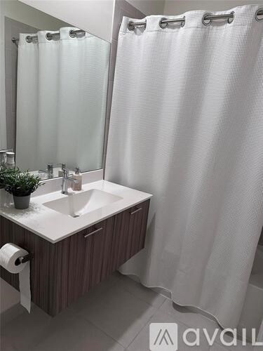A bathroom with a white sink and a white shower curtain.