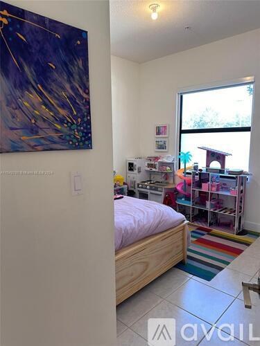 A bedroom with a bed, a painting on the wall, and a window.