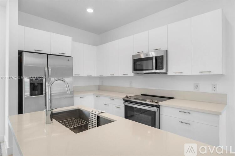 A kitchen with white cabinets and a stainless steel refrigerator.
