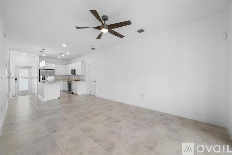 A spacious empty room with a ceiling fan and lighting.