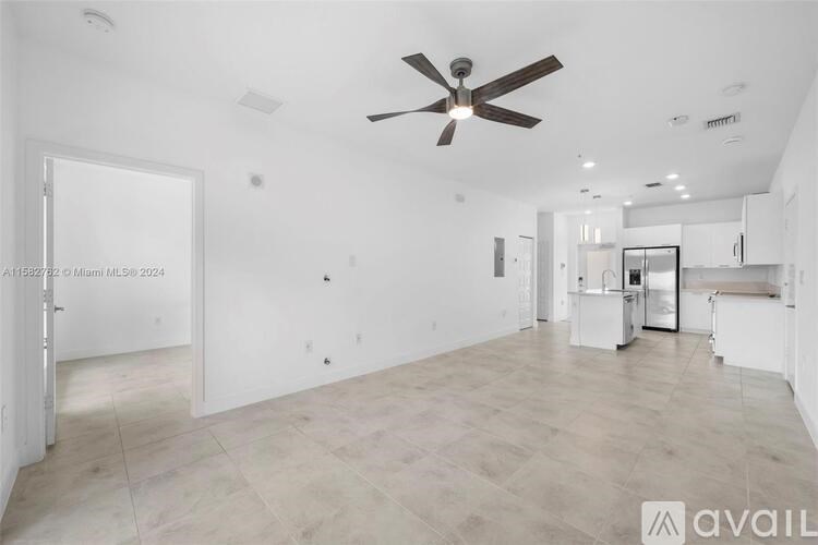 A spacious, empty room with a ceiling fan and lighting fixtures.