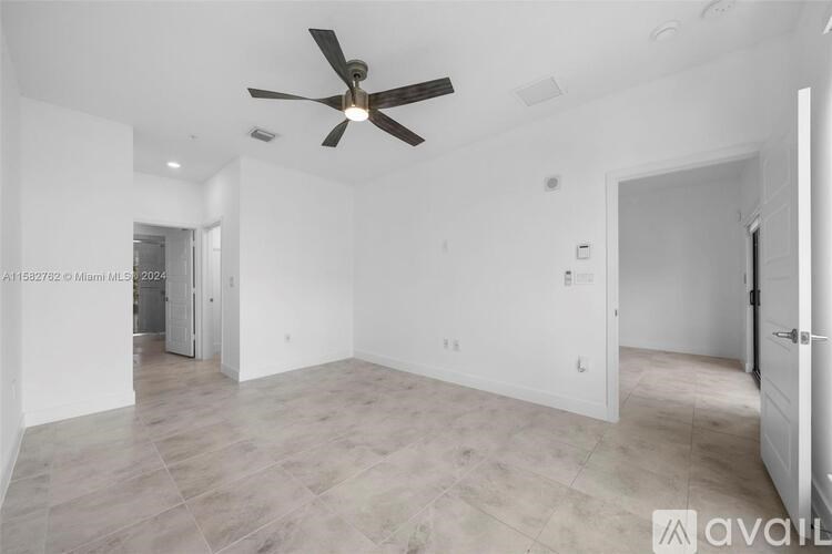 A spacious room with a ceiling fan and lighting fixtures.
